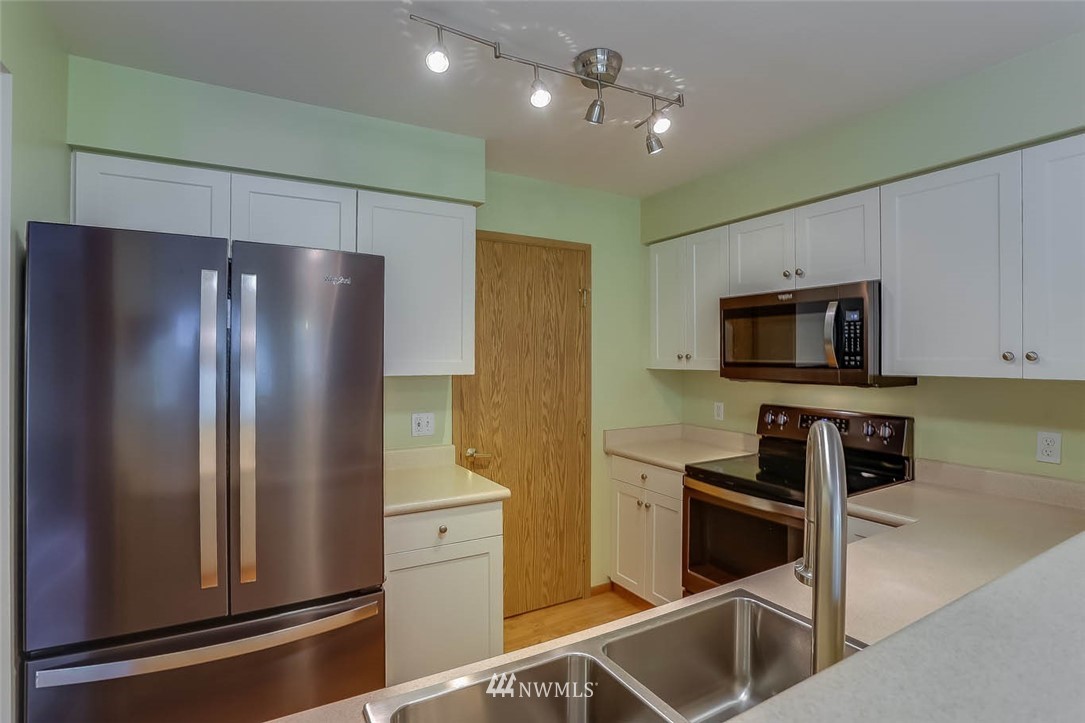 15150 140th Way Southeast, Unit N102 Renton, WA 98058 - Photo 10 of 20 a kitchen with stainless steel appliances granite countertop a refrigerator and a stove top oven