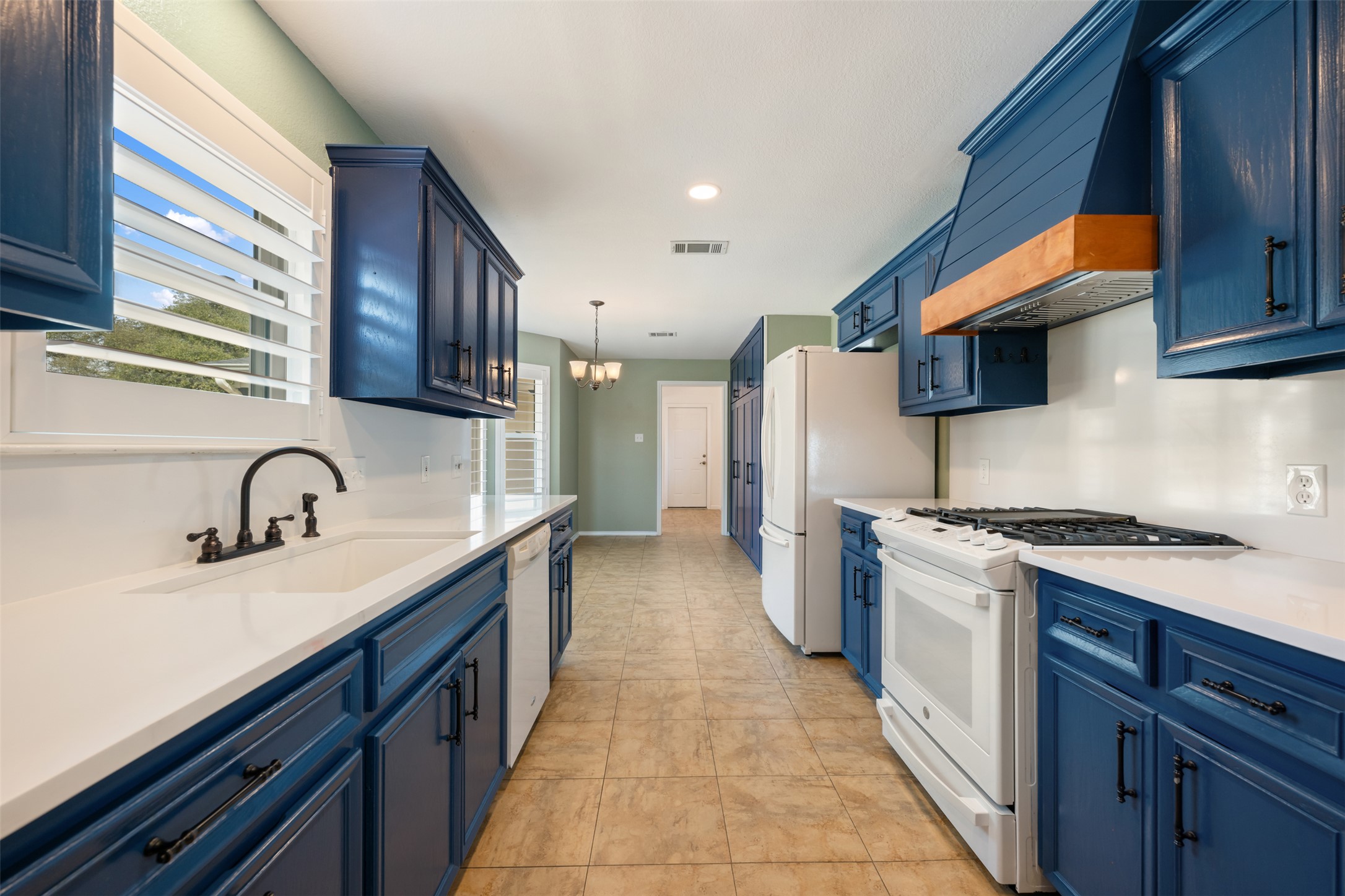 104 Sunset Road Georgetown, TX 78633 - Photo 12 of 40 Kitchen with blue cabinetry and white appliances