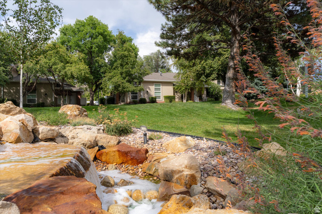 888 East 6895 South Midvale, UT 84047 - Photo 48 of 54 Scenic landscaped water feature with natural stone accents and flowing waterfall, creating a tranquil and inviting outdoor environment.