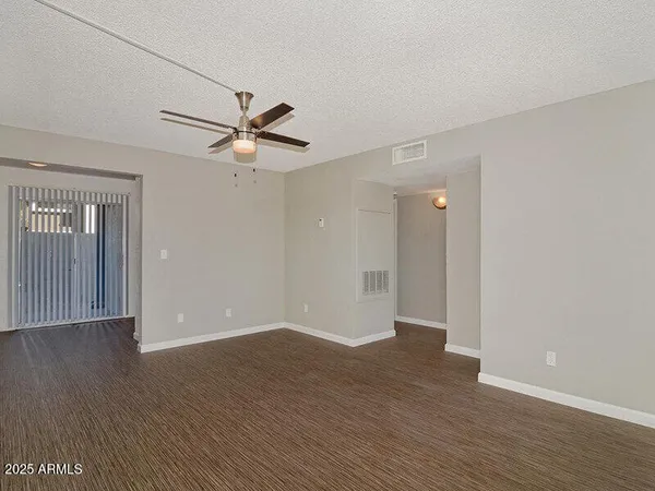 an empty room with wooden floor and a ceiling fan