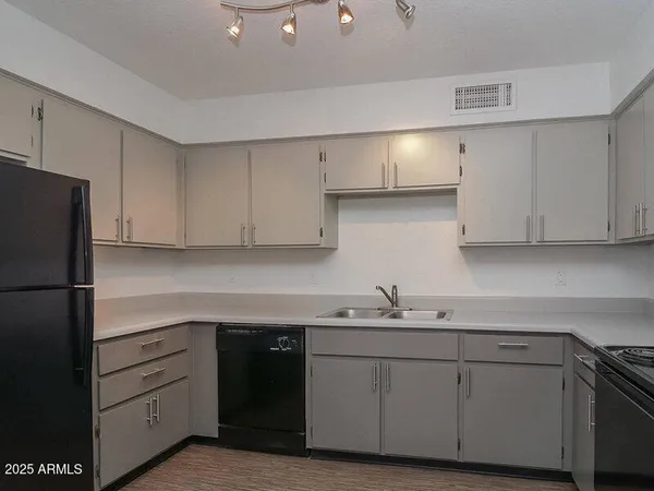 a kitchen with a sink dishwasher a refrigerator and cabinets