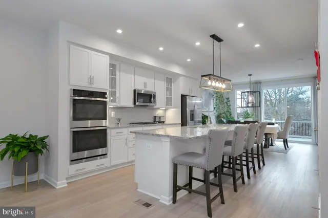 a large kitchen with dining table chairs stainless steel appliances and potted plants