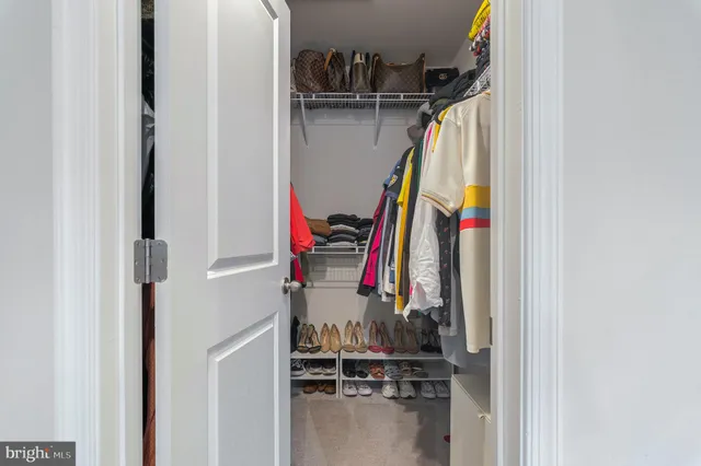 a view of walk in closet with clothes and shoes