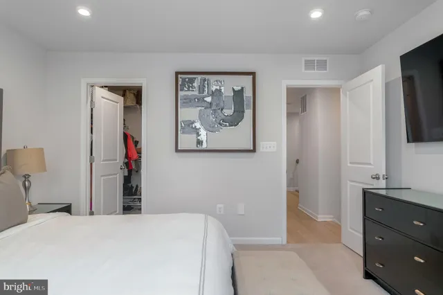 a bedroom with a bed and a flat tv screen on dresser