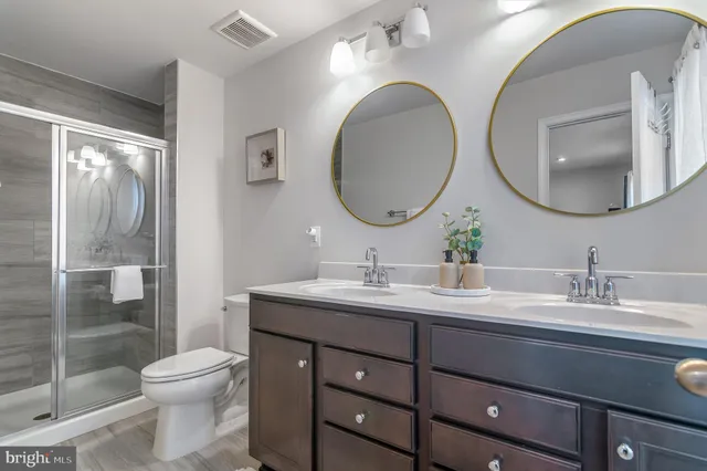 a bathroom with a toilet a double vanity sink and a mirror