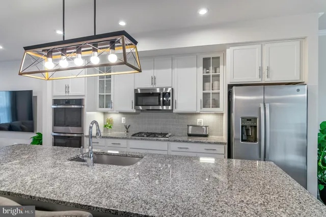a kitchen with stainless steel appliances granite countertop a sink a stove and a refrigerator