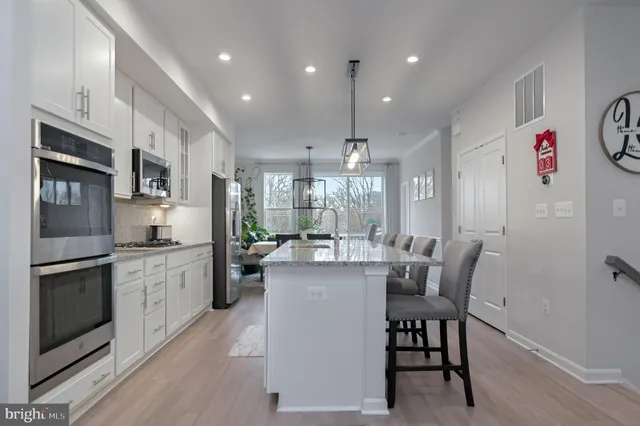 a kitchen with stainless steel appliances granite countertop a refrigerator a stove top oven a sink dishwasher and white cabinets