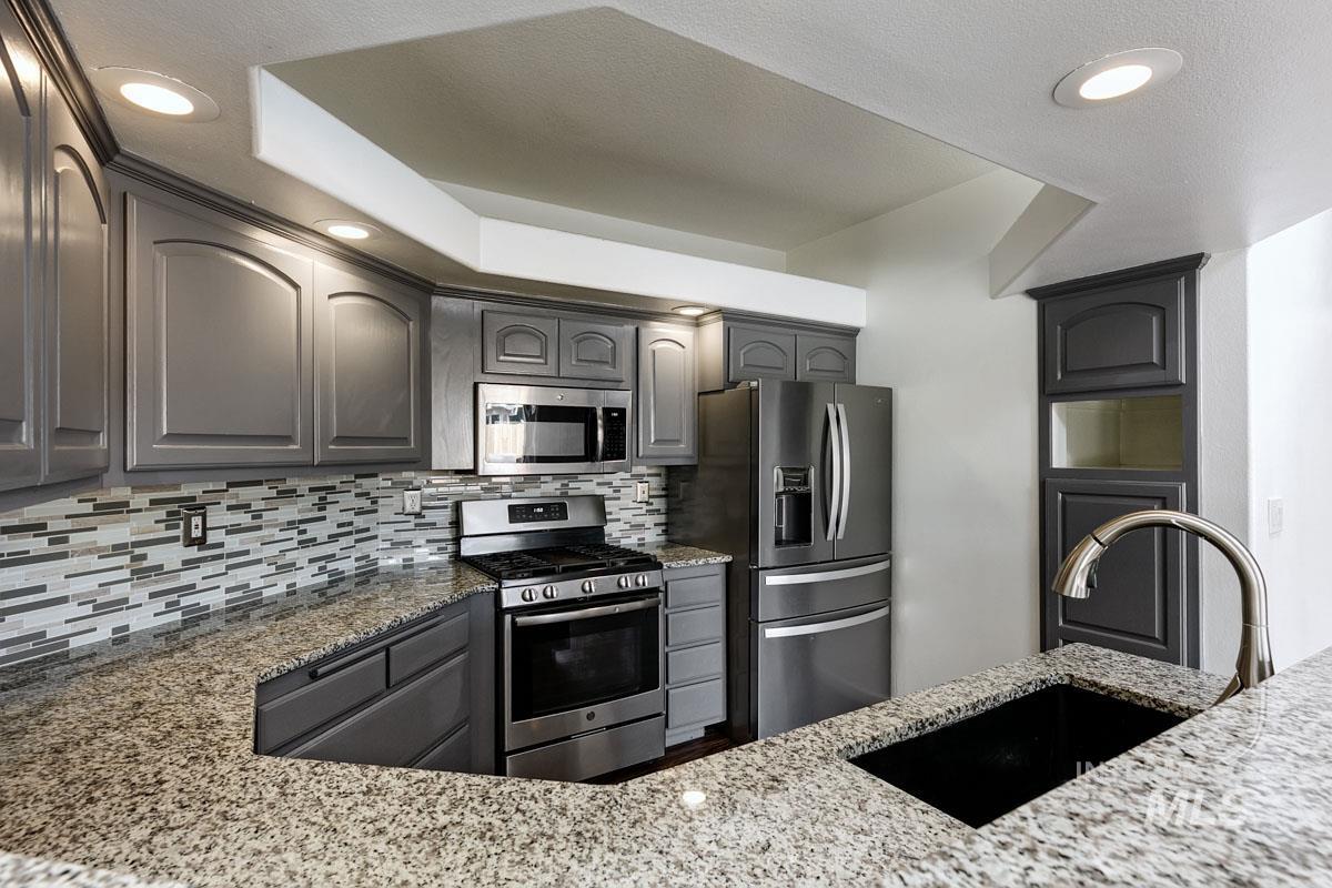 2575 S Bayou Meridian, ID 83642 - Photo 7 of 30 Granite countertops, stainless steel appliances, mosaic tile backsplash, gray cabinetry, and recessed lighting