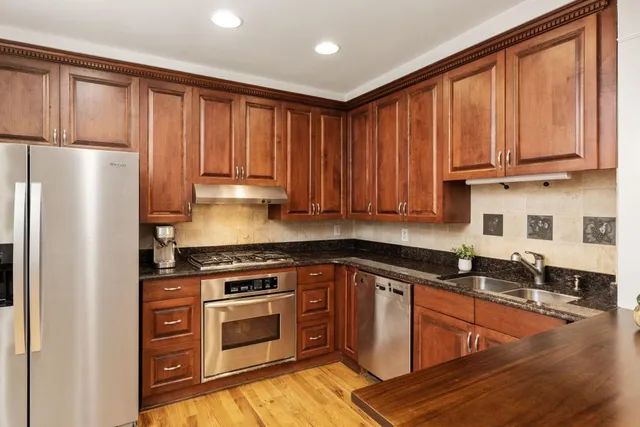 a kitchen with granite countertop wooden cabinets and a stove top oven