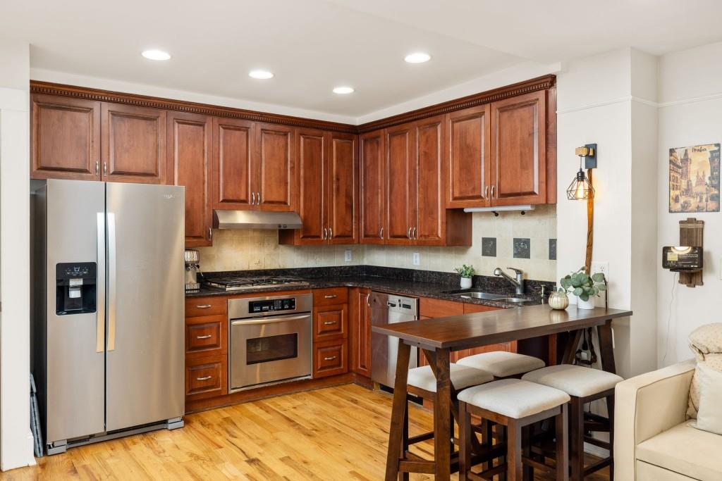259 14th Street Northeast, Unit B103 Atlanta, GA 30309 - Photo 3 of 33 a kitchen with stainless steel appliances granite countertop a stove a refrigerator a sink a dining table and chairs