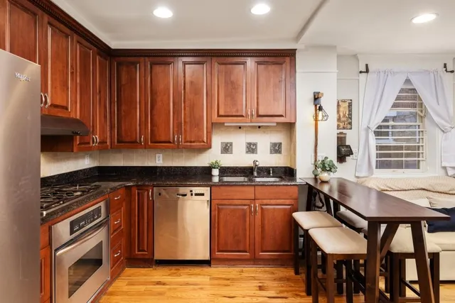 a kitchen with stainless steel appliances granite countertop a stove top oven a sink dishwasher and cabinets with wooden floor