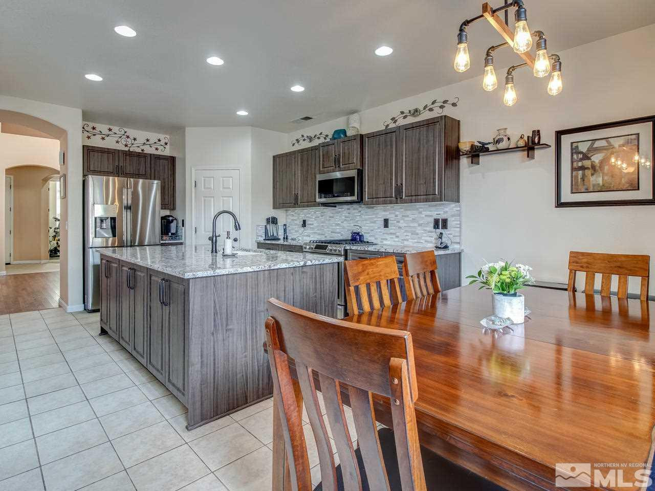 1723 Cavern Drive Reno, NV 89521 - Photo 8 of 25 a kitchen with stainless steel appliances kitchen island granite countertop a table chairs and a refrigerator
