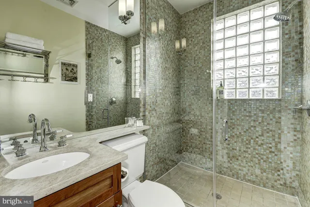 a bathroom with a granite countertop sink toilet a mirror and shower