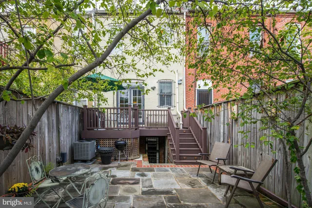 a view of a house with wooden deck and a large tree