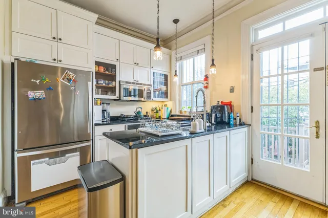 a kitchen with stainless steel appliances granite countertop a refrigerator a sink and white cabinets