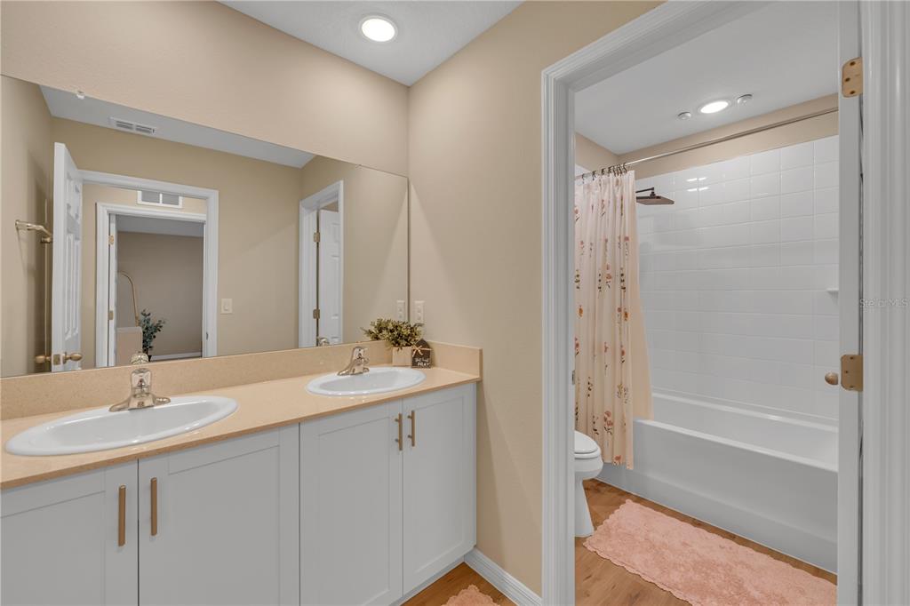 12710 Hysmith Loop Parrish, FL 34219 - Photo 25 of 45 a bathroom with a double vanity sink toilet mirror and bathtub