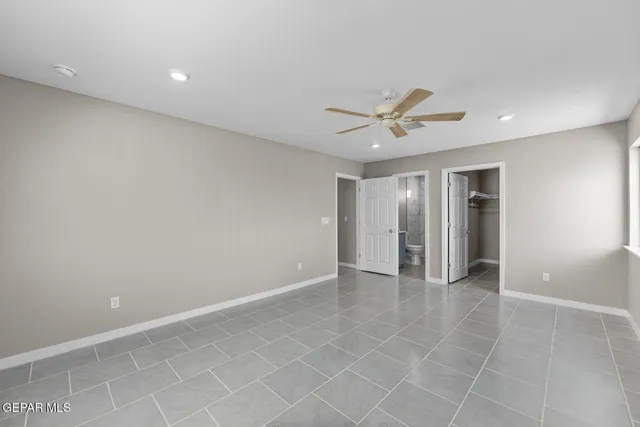 an empty room with closet and a ceiling fan