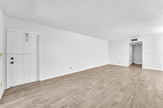 an empty room with wooden floor cabinet and windows