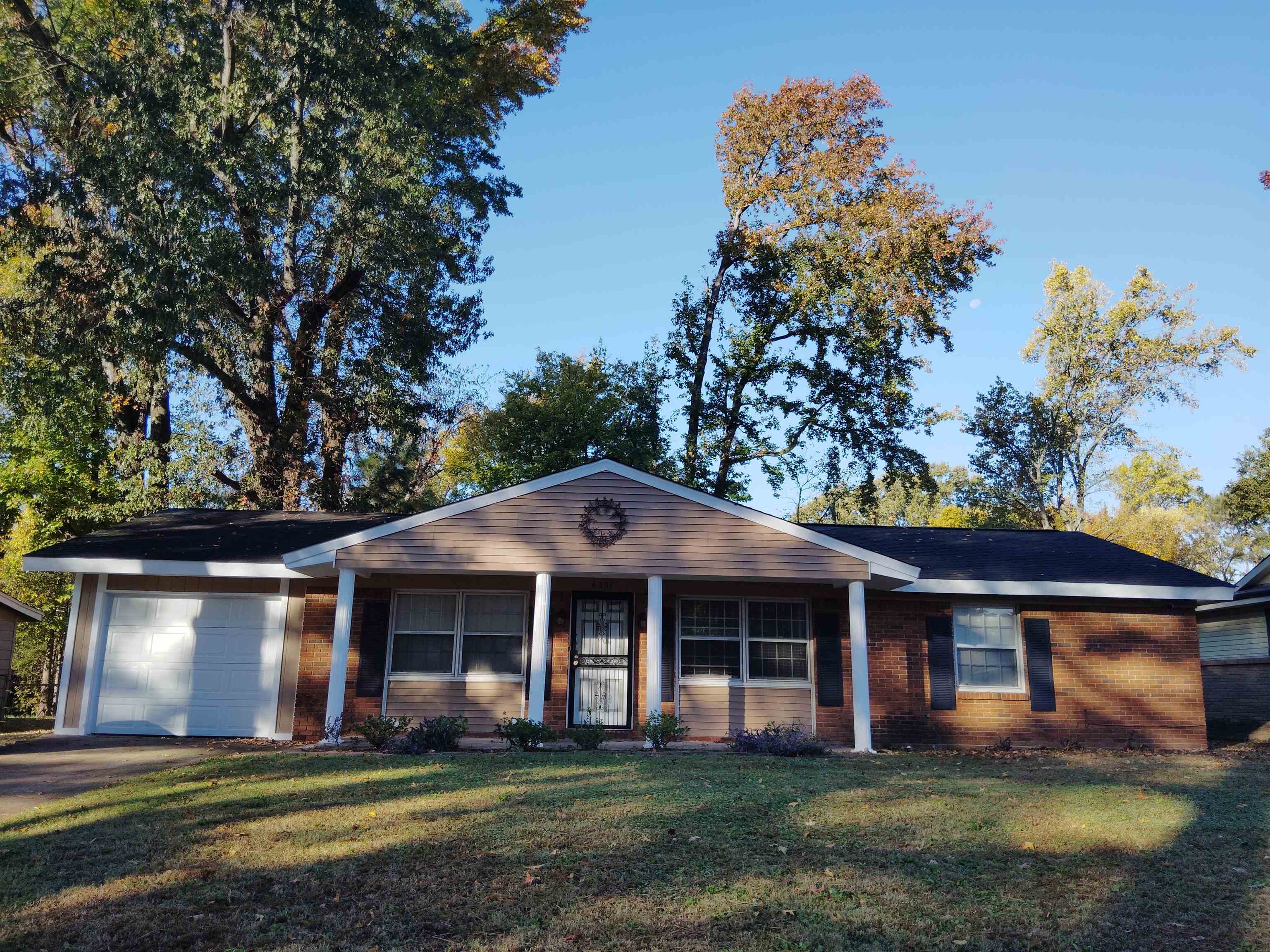 a front view of a house with a garden and trees