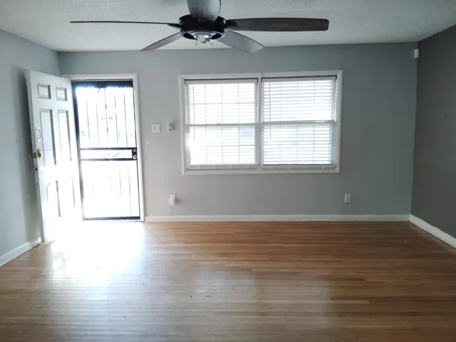 an empty room with wooden floor and windows