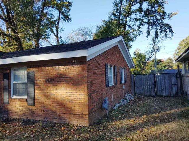 a view of a house with a small yard plants and large tree