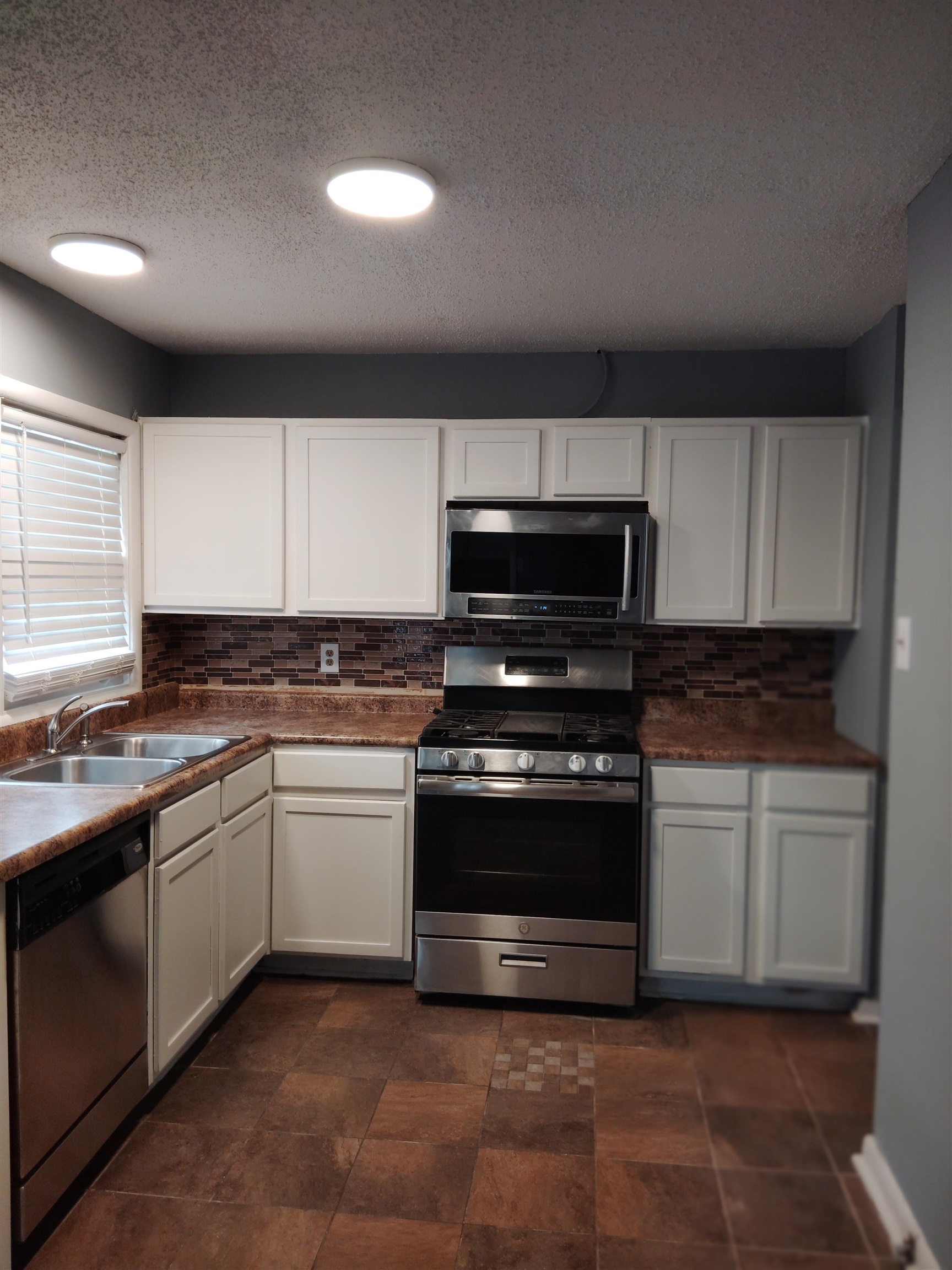 4307 Sidney Road Memphis, TN 38116 - Photo 7 of 18 Kitchen with appliances with stainless steel finishes, a textured ceiling, white cabinetry, tasteful backsplash, and dark countertops