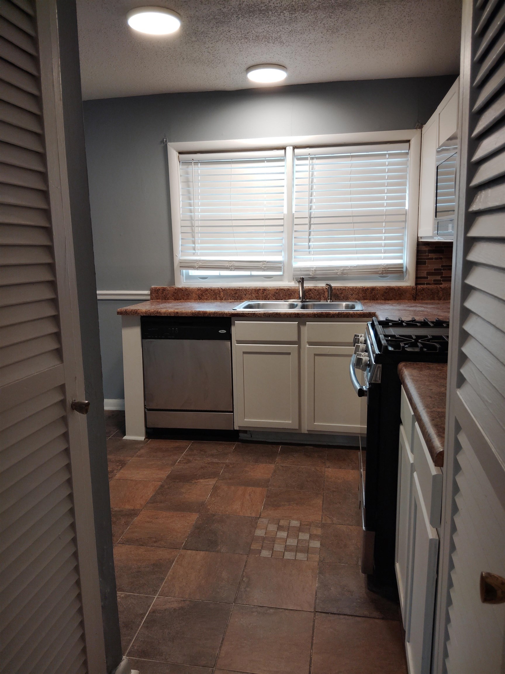 4307 Sidney Road Memphis, TN 38116 - Photo 8 of 18 Kitchen featuring dark countertops, white cabinets, black gas range oven, dishwasher, and a textured ceiling