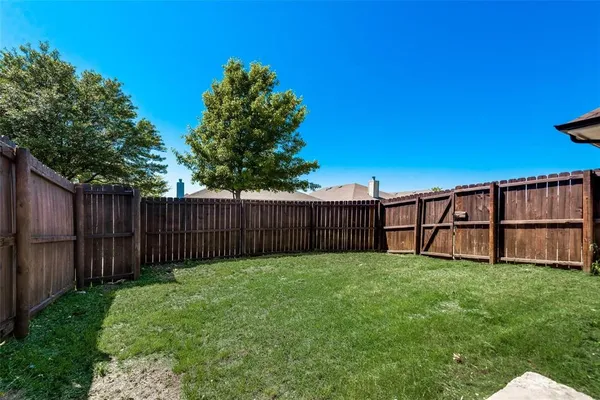 a view of backyard with wooden fence and trees