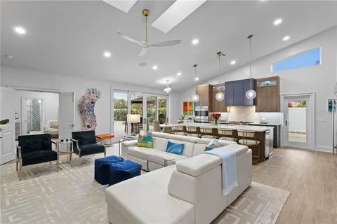 a living room with furniture kitchen view and a wooden floor