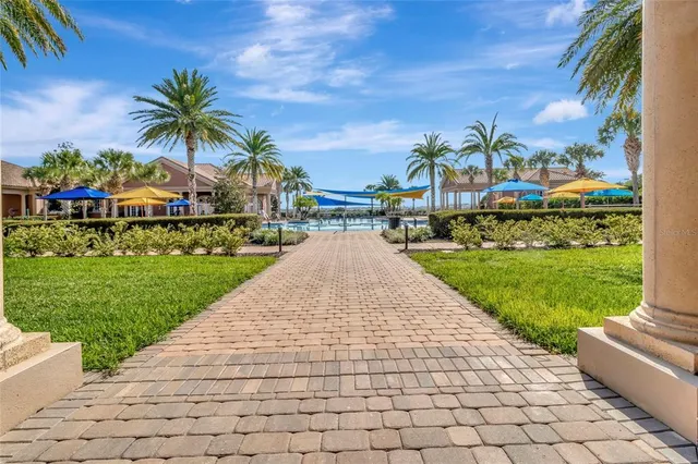 a view of a white house with a yard plants and palm trees