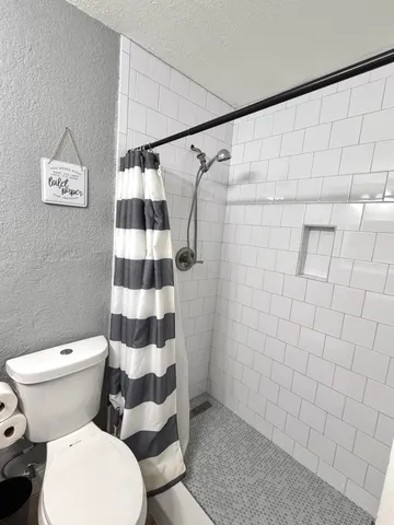 a white toilet sitting next to a shower curtain