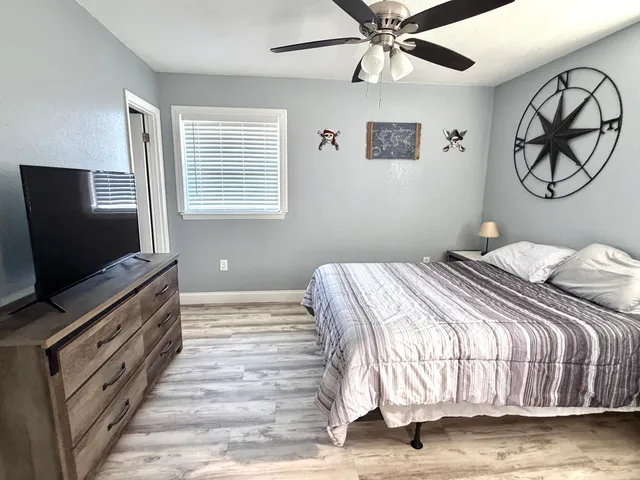 a bedroom with a large bed and a flat tv screen on dresser