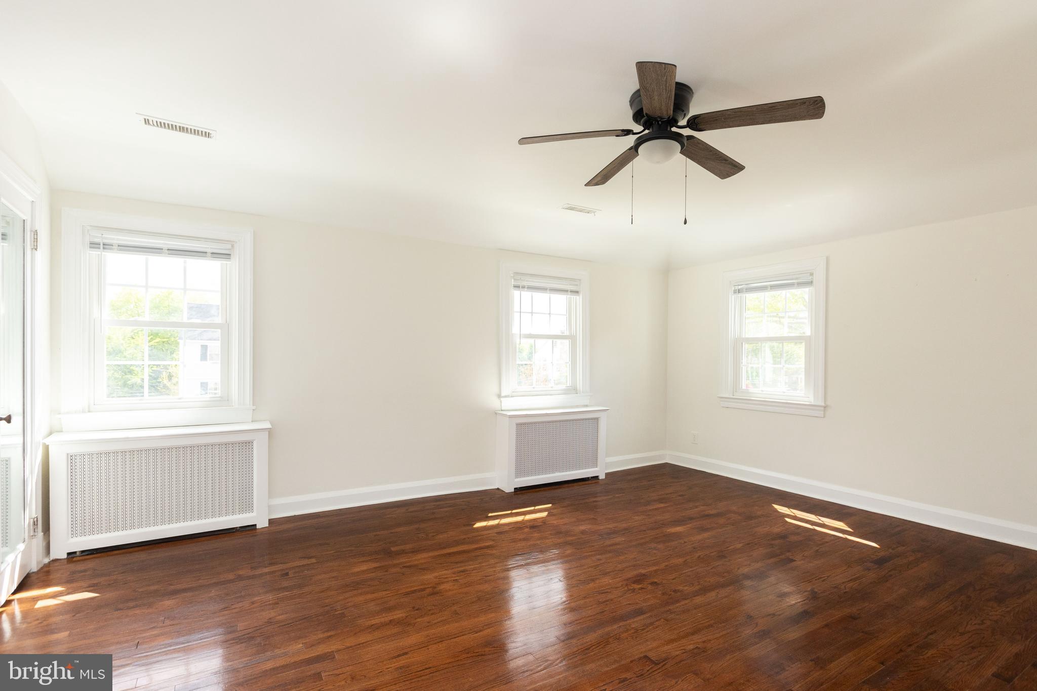 710 Regester Avenue Baltimore, MD 21212 - Photo 31 of 48 an empty room with wooden floor fan and windows
