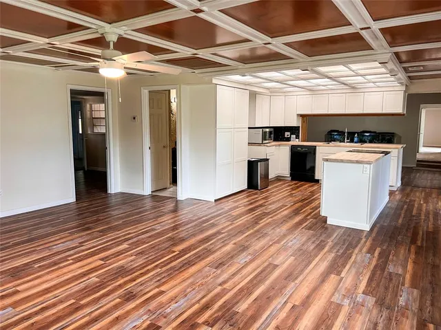 a view of a room with wooden floor and a kitchen