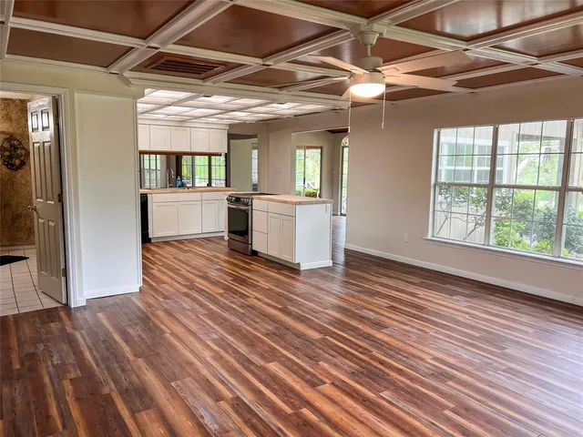 a view of a room with wooden floor and a kitchen space