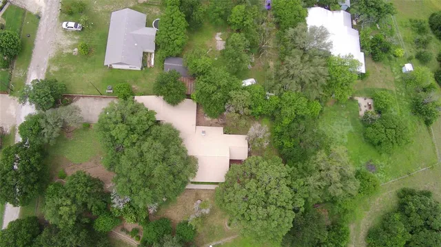 an aerial view of residential house with outdoor space and trees all around