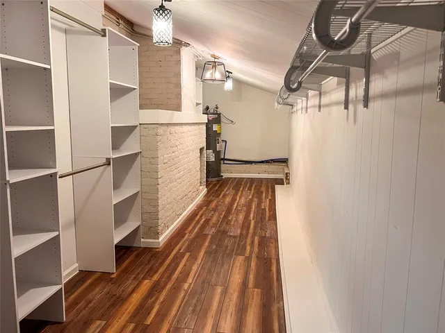 a walk in closet with wooden floor