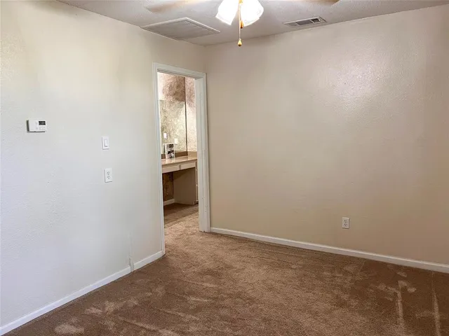an empty room with a chandelier fan and windows
