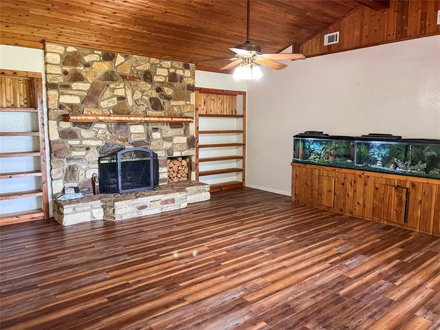 an empty room with wooden floor fireplace and windows