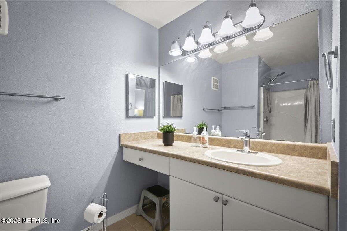 10961 Burnt Mill Road, Unit 1132 Jacksonville, FL 32256 - Photo 22 of 47 a bathroom with a granite countertop sink a toilet and a mirror