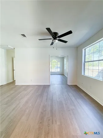 an empty room with wooden floor and windows