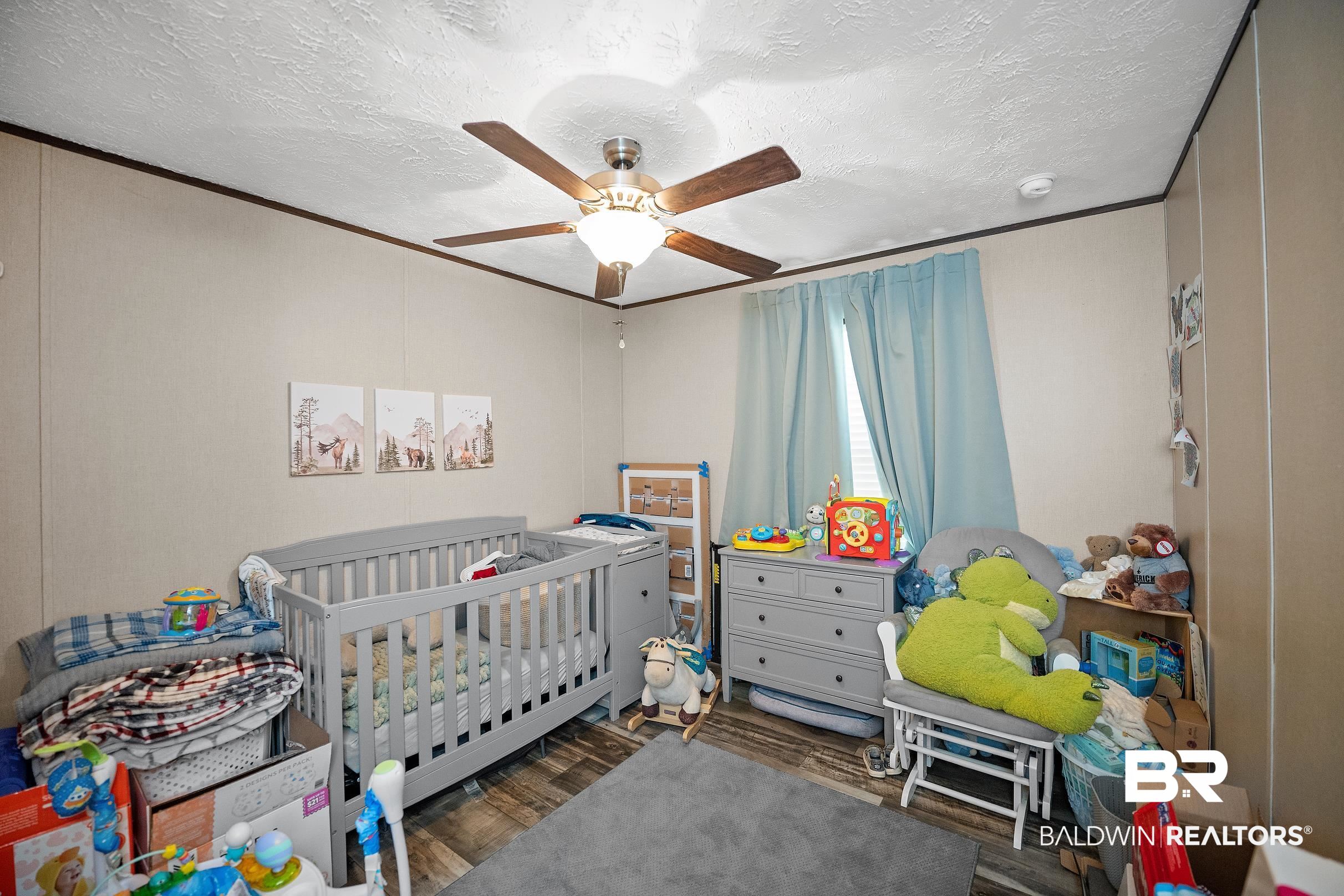 8630 Allison Lane Wilmer, AL 36587 - Photo 21 of 31 Bedroom with a textured ceiling, dark wood-style flooring, a crib, ceiling fan, and ornamental molding