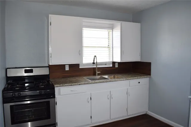 a kitchen with granite countertop a sink and a stove
