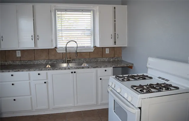 a kitchen with granite countertop a sink stove and cabinets