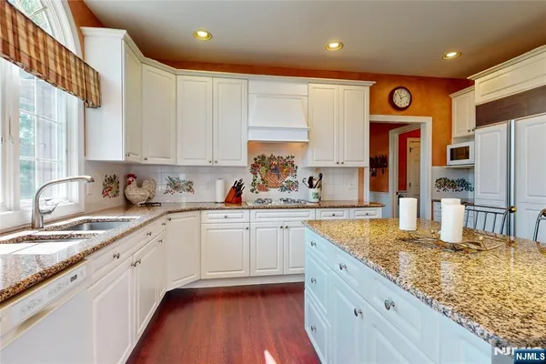 a large kitchen with granite countertop a sink stainless steel appliances and cabinets