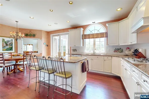 a kitchen with granite countertop a stove a sink a dining table and chairs