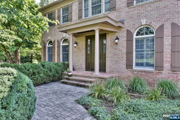 front view of a brick house with a large windows and flower plants