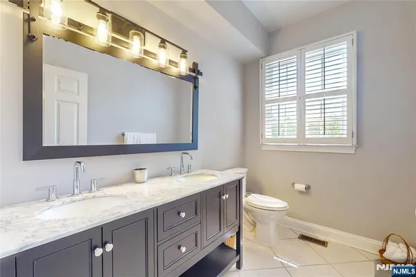 a bathroom with a granite countertop double vanity sink a mirror and a toilet