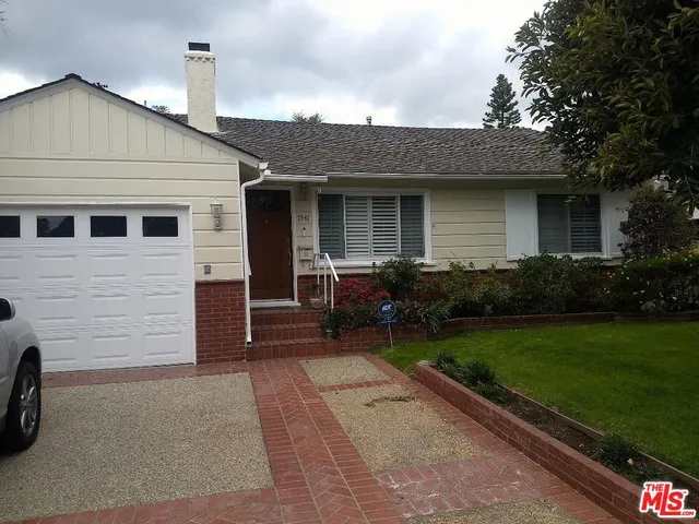 a front view of a house with a garden and chairs