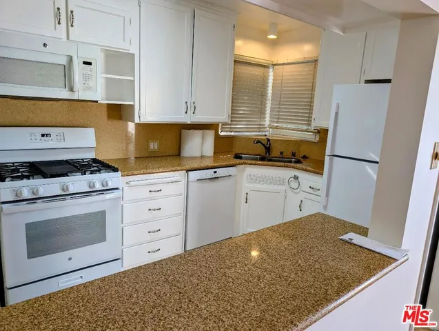 a kitchen with granite countertop cabinets stainless steel appliances and a sink
